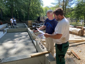Rico Ulbricht (l.), Stadtplaner in Mittweida, schaut sich zusammen mit Polier Daniel Jacob das Fundament für die neue Voliere am Schwanenteich in Mittweida an.