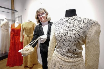 Kuratorin Katrin Färber an einem einst weißen Hochzeitskleid, das in einer neuen Ausstellung in der Fabrik der Fäden zu sehen ist.