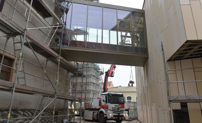Der gläserne Brückengang verbindet das historische Gebäude links mit dem modernen Erweiterungsbau. Letzterer ist mit hinterlüfteten Keramiktafeln verkleidet worden. 
