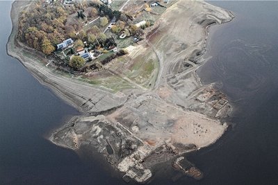 Dieses Luftbild dokumentiert Reste des in der Talsperre versunkenen Dorfes Pöhl im Jahr 2018 bei Niedrigwasser. Die rötliche Fläche zeigt die Lage des einstigen Schlosses Pöhl, links daneben (in Grau) befand sich der Schlosspark. Die Mauern am und im Wasser sind Überreste von Wirtschaftsgebäuden.