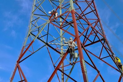 Mitarbeiter der Firma beim Anstreichen eines Hochspannungsmasts.