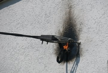 Die brennende Elektroleitung an der Hauswand. 