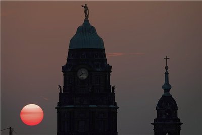 Hinter Rathausturm (l) und Kreuzkirche versinkt die Sonne am Dresdner Abendhimmel. Endet nun auch Sachsens Sonderweg beim Buß- und Bettag? Selbst die CDU will die Arbeitnehmer im Freistaat bei der Pflegeversicherung nicht mehr stärker belasten als Arbeitgeber. Foto: Sebastian Kahnert/dpa-Bildfunk