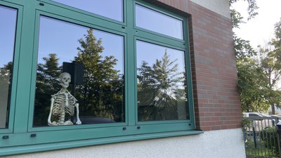 Zufall oder passiver Widerstand? Skelett in Schulzimmer grüßt Kreistagsabgeordnete vor Kreistagssitzung in Gymnasiumsmensa.