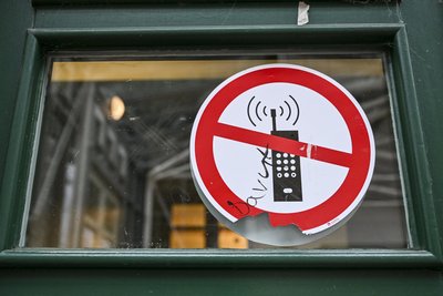 Ein Schild mit einem durchgestrichenen Handy-Symbol weist in einer Schule auf ein Handyverbot hin.
