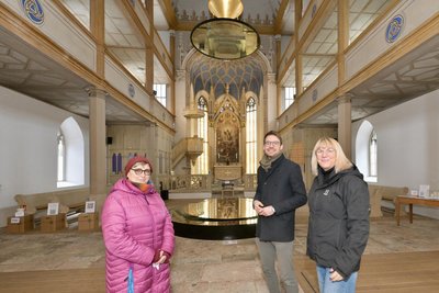 Christine Wagner (links) und Jacqueline Schöniger gehören zu den Kirchenöffnern. Sie haben Pfarrer Raphael Weiß in der Hospitalkirche Lößnitz in die Mitte genommen.