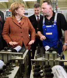 Bundeskanzlerin Angela Merkel (CDU) lässt sich am Montag im Werk des Automobilzulieferers Continental in Limbach-Oberfrohna (Sachsen) vom Continental Vorstandsvorsitzenden Elmar Degenhart und Mitarbeiter Karsten Lämmel (r) die Funktion von Piezo Injektoren erläutern. Der Konzern hat hier sein Kompetenzzentrum für Piezo Common Rail Injektoren.