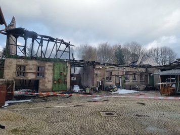 Stunden nach dem Ausbruch des Brandes auf dem Vierseitenhof in Uhlsdorf qualmte es noch immer. Von den darin angestellten Fahrzeugen blieben nur noch Gerippe übrig. 