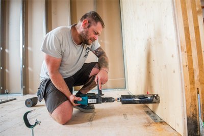 Auch im Inneren laufen Arbeiten: Holzbaumonteur Johannes Litfin bohrt einen Wanddurchbruch für die Fußbodenheizung.