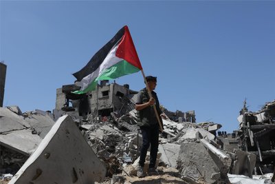 Ein Palästinenser hält in Chan Junis die palästinensische Fahne in der Hand, während er auf Trümmern durch israelischen Beschuss steht. Norwegen, Irland und Spanien werden Palästina demnächst als Staat anerkennen.