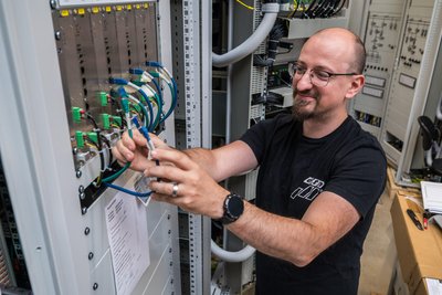 Elektroinstallateur Andy Petzold beim Anschließen von Netzwerkkabeln an einen Schaltschrank. Die ETO hat rund 160 Beschäftigte.