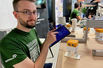 Jonas Werner von der Fakultät für Maschinenbau der TU Chemnitz zeigt eine Roboter-Steuerung auf einem Tablet-Computer.