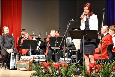 Klingenthals Oberbürgermeisterin Judith Sandner (Freie Wähler) bei der Festrede zum 60-jährigen Jubiläum des Akkordeonorchesters. Ganz links Dirigent Richard Wunderlich.