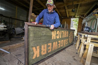 Benjamin Hahn nimmt in seiner Werkstatt das Schild fürs fiktive „Sägewerk Uhlich“ auseinander, das während des jüngsten Drehs am Lichtensteiner Sägewerk von Reiner Süß angebracht war. Hahn hatte diese Location empfohlen.