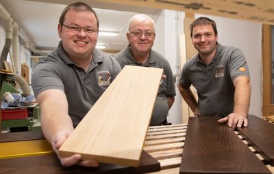 Drei Tischlermeister mit ihrem bevorzugten Werkstoff: Wilhelm Hiller (Mitte) mit seinen Söhnen und Nachfolgern Daniel (links) und Stefan. 