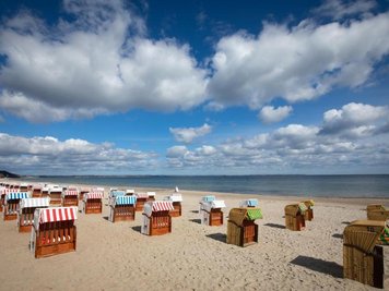             Geschlossene Strandkörbe stehen auf einem fast menschenleeren Strand an der Ostsee.
