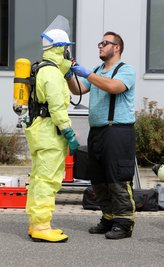 Ein Feuerwehrmann erhält Hilfe von einem Kollegen.