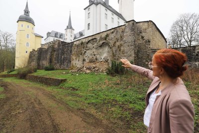 Diana Kümmel-Guszan zeigt den Schaden an der Mauer von Schloss Purschenstein aus dem Jahr 2023.