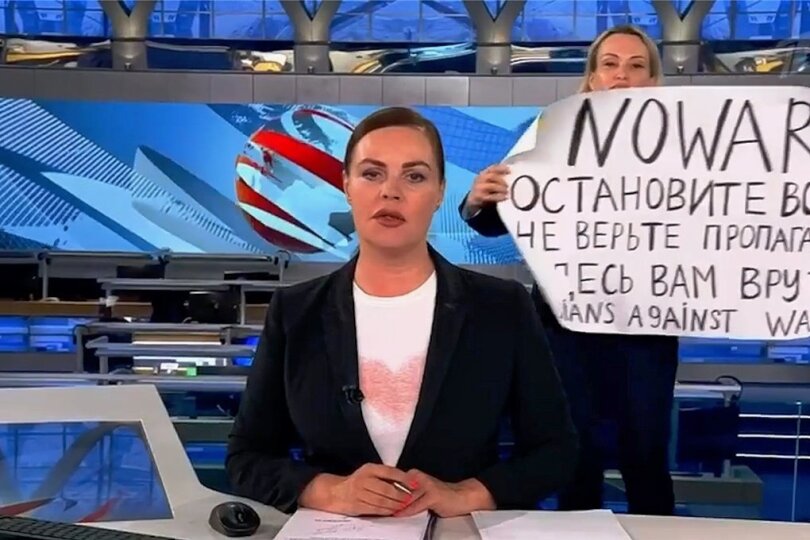Das Bildschirmfoto aus der abendlichen Hauptnachrichtensendung des russischen Staatsfernsehens zeigt die Protestaktion von Marina Owsjannikowa (Hintergrund) vor einer Woche. Seitdem läuft die Sendung laut Mitarbeitern mit einem Zeitversatz von mindestens 30 Sekunden. 