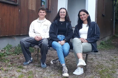 Kody Schettler, Emma und Anja Weidlich (v. l.) sitzen vor dem Ex-Sportlerheim in Stützengrün.