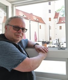 Thomas Erler schaut aus dem Filmprojektfenster zu, wie im Schlosshof Leinwand aufgebaut wird.