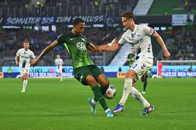 Wolfsburgs Jeanuël Belocian (l) stoppt den Paderborner Jonah Sticker. 