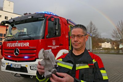 Wehrleiter Kai Götze mit dem Plüsch-Elefant vor dem neuen Fahrzeug der Feuerwehr in Meerane.