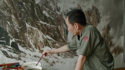 Ein Maler im Mansuade Art Studio, der Berge so malen will, dass Betrachter Kraft schöpfen können.