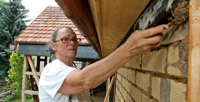Eva Burkert, Restauratorin im Mauer- und Lehmbauhandwerk, arbeitet an einer der Außenwände. Die Mauer besteht aus Lehmziegeln.