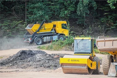 Auf der Baustelle Hakenkrümme herrscht Hochbetrieb. Im Hintergrund verlässt ein Laster das Gelände über die Zufahrtsstraße in Richtung Becherweg.