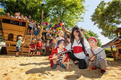 Johann und Heinrich und die anderen Kinder der Kita Pusteblume freuen sich mit Pirat, Erzieherin Silke Berger, über das neue Spielgerät.