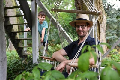 Eine der Lieblingsstellen von Alexander Christoph im Garten: Ein Hängesessel unterm Baumhaus. Im Hintergrund ist sein Sohn zusehen.