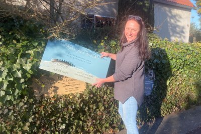 Floristin Katja Anders mit dem neuen Schild das künftig auf ihre Natur-Resilienz-Werkstatt hinweist.  Bernd Appel