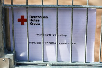 Ein Schild am Absperrzaun verrät, was geplant ist, hier allerdings allgemein gehalten, als Notunterkunft für Flüchtlinge.