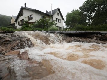 Wasser läuft bei Heimbach an einem Haus vorbei den Hang hinunter
