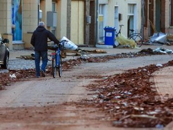 Ein Einwohner von Bützow schiebt sein Rad über die Hauptstraße der zerstörten Altstadt. Überall liegen die Ziegel von abgedeckten Dächern.