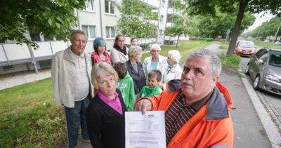Marita und Steffen Wünsch (vorn) und andere Mieter der Häuser Carl-von-Ossietzky-Straße 107, 109 und 111 mit dem Aushang, in dem ihnen der Versorger Eins die Einstellung der Trinkwasserlieferung und das Abschalten des Stroms für das Hauslicht für kommenden Montag ankündigt hatte.