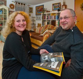 Hanna und Dmytro Remestvenskyy vor einem noch unbemalten Regal in ihrem Wohnzimmer, die meisten anderen sind mosaikverziert. 