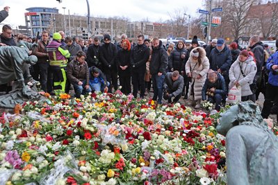 Menschen legen am offiziellen Trauerort vor der Johanniskirche in Magdeburg Blumen und Kerzen ab.