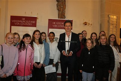 Eine Schülerschar der Friedensschule mit Schulleiter Uwe Zimmermann, der das Nagelkreuz hält.