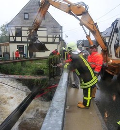 In Bockau wurde am Kapellenbach eine Gasleitung destabilisiert. Feuerwehrleute befestigten sie vorerst an einem Stahlträger.