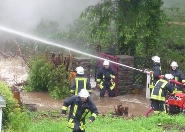 Die Feuerwehr während der Flut bei einem Löscheinsatz! Eine Gartenlaube zwischen Floßgraben und Zschorlaubach in Aue-Neudörfel brannte lichterloh (Bild links). Die Feuerwehr rückte an, um die Flammen zu löschen. Zuerst hatten die Einsatzkräfte aber mit dem Hochwasser zu tun. Der Bach war über sein Ufer getreten. Das erschwerte die Arbeiten massiv. Die Kameraden mussten sich durch das Wasser kämpfen.