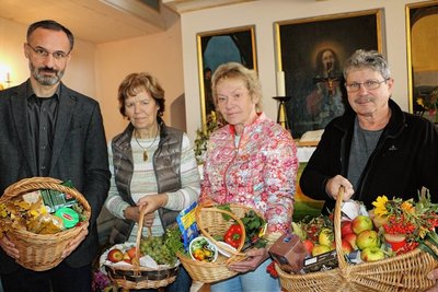 Pfarrer Rainer Sörgel, Waltraud Fischer, Helferin aus Mühltroff, sowie Konstanze Schumann und Henry Köhler vom Verein Arbeitsloseninitiative Sachsen (von links) mit den Erntedankgaben in der Mühltroffer Schlosskirche. 