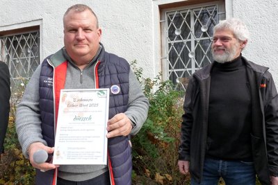 Bürgermeister Knut Schreiter und René Oesterreich zeigen die Urkunde mit dem „schennsten Gälner Wort“.