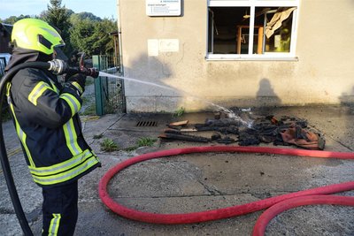 Aus dem Brandraum geholte, verkohlte Materialien, darunter Holzteile und Bodenmatten, wurden vor dem Wäschereigebäude noch abgelöscht.