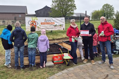 Rolf Weigand und Vertreter der Sparkasse freuen sich mit den Kindern über die neuen Beete.