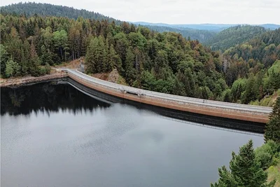 Die Talsperre heute: Stein um Stein wurde die Mauer errichtet, 211.150 Tonnen Handarbeit. Rechts das Staumeisterhaus.