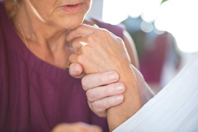 Eine Frau hält die Hand ihres an Demenz erkrankten Mannes.