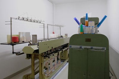 Links steht die Flachstrickmaschine, eine „Textima“-Fabrikat, hergestellt vom „VEB Wirkmaschinenbau Karl-Marx-Stadt“ und rechts die Spulmaschine aus Limbach-Oberfrohna.