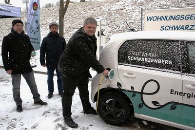 Stadtwerke-Geschäftsführer Sascha Wehrmann "zapft" Strom an der neuen Station. Zur Eröffnung im Flockenwirbel dabei: Enrico Schaarschmidt (l.) und Michael Förster von der Wohnungsgenossenschaft. 